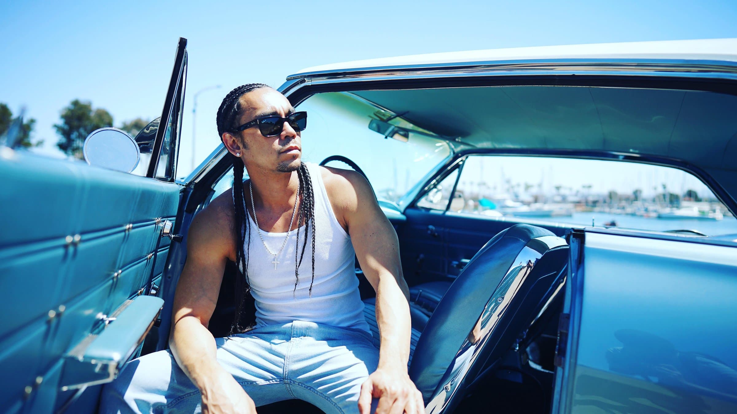 Kekoa leaning out of a vintage blue car